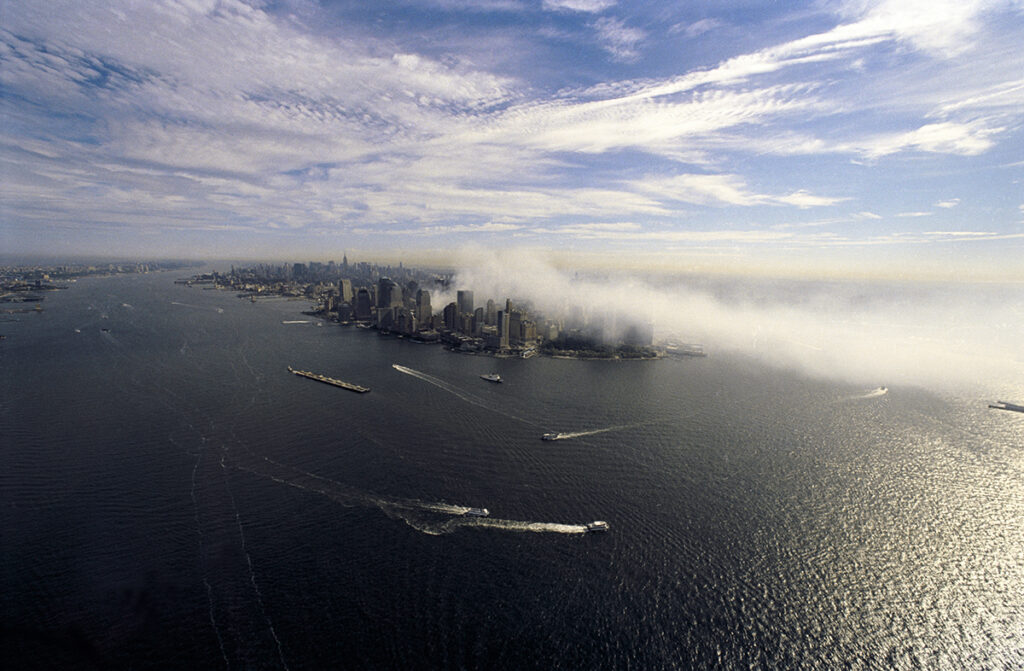 Aerial view of Lower Manhattan post-9/11, with smoke rising from Ground Zero, captured by Gregg Brown.